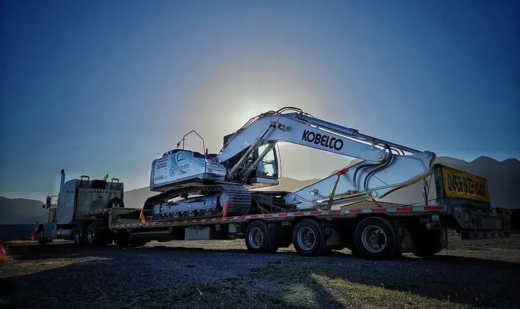 Open Deck & LTL Trailer Bowline Logistics flatbed truck carrying a Kobelco excavator during sunrise, showcasing open deck freight capabilities