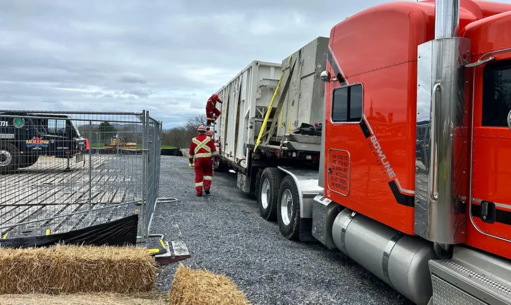 Storage and Transloading Trailer Bowline Logistics crew loading containerized freight onto a flatbed trailer in a fenced yard for transloading or storage services