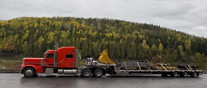 Bowline Logistics flatbed trailer driving through forestry Bowline Logistics flatbed trailer driving through forestry