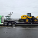 Bowline truck hauling large industrial equipment on a flatbed trailer on a rural road in Western Canada.