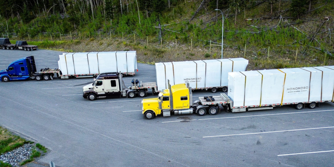 Heavy haul trucks transporting modular units on flatbed trailers during construction season in Western Canada